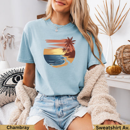 Light blue t-shirt with sunset beach graphic and palm trees.