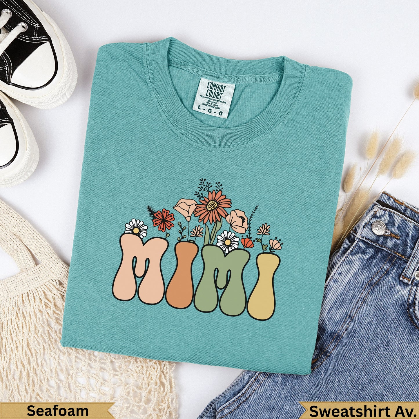 Teal sweatshirt with "MIMI" in colorful retro lettering and floral accents.