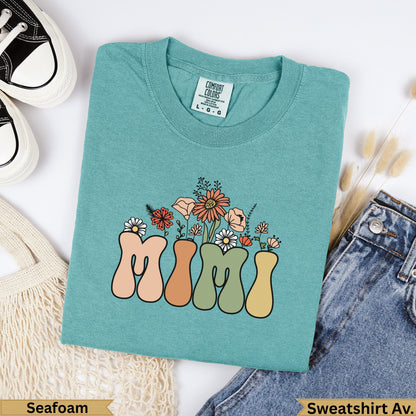Teal sweatshirt with "MIMI" in colorful retro lettering and floral accents.