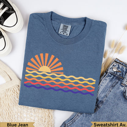 Blue Jean Comfort Colors sweatshirt with a colorful sunset and wavy ocean graphic.