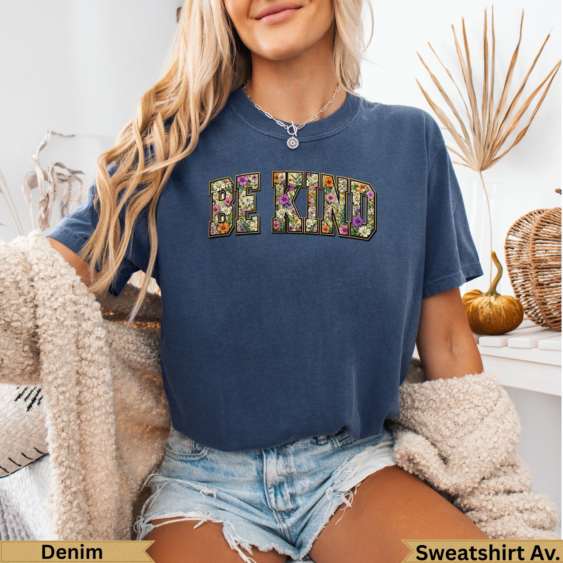 Navy sweatshirt with "BE KIND" in floral letters, worn by a woman.