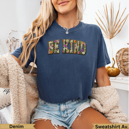 Navy sweatshirt with "BE KIND" in floral letters, worn by a woman.