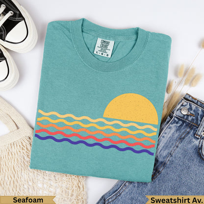 Teal t-shirt with colorful wavy lines and a sun graphic, "Seafoam" text.