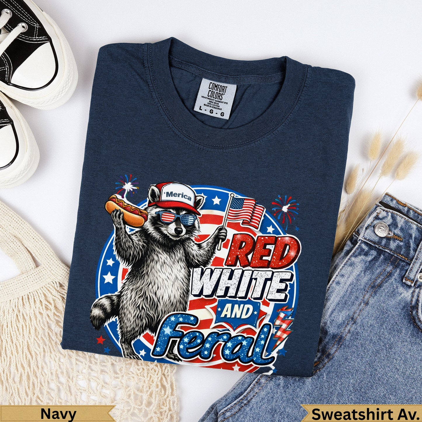 Navy sweatshirt with raccoon wearing sunglasses and holding a hot dog, "RED WHITE AND Feral" text.