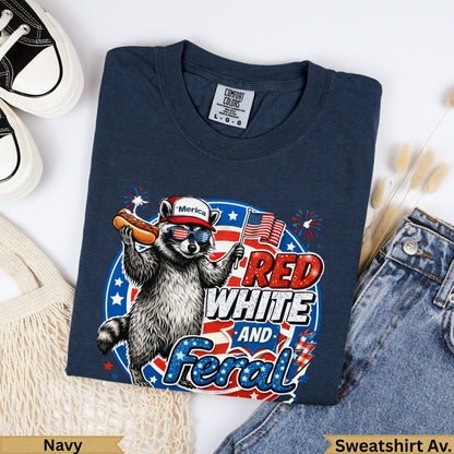 Navy sweatshirt with raccoon wearing sunglasses and holding a hot dog, "RED WHITE AND Feral" text.
