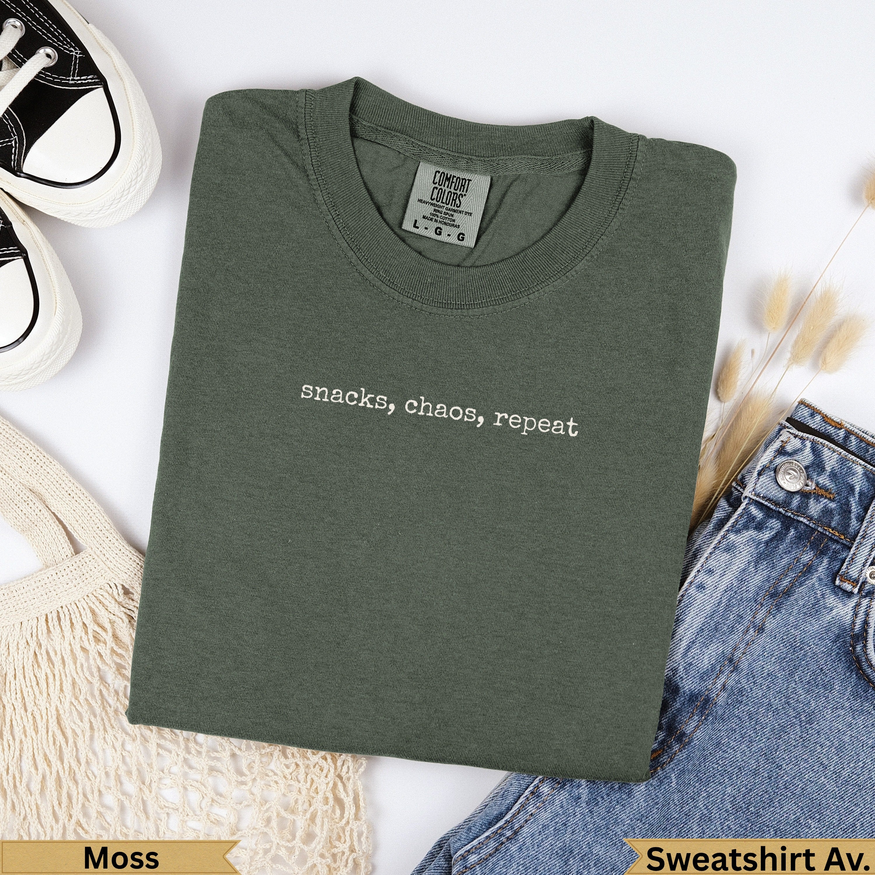 Olive green t-shirt with "snacks, chaos, repeat" text.