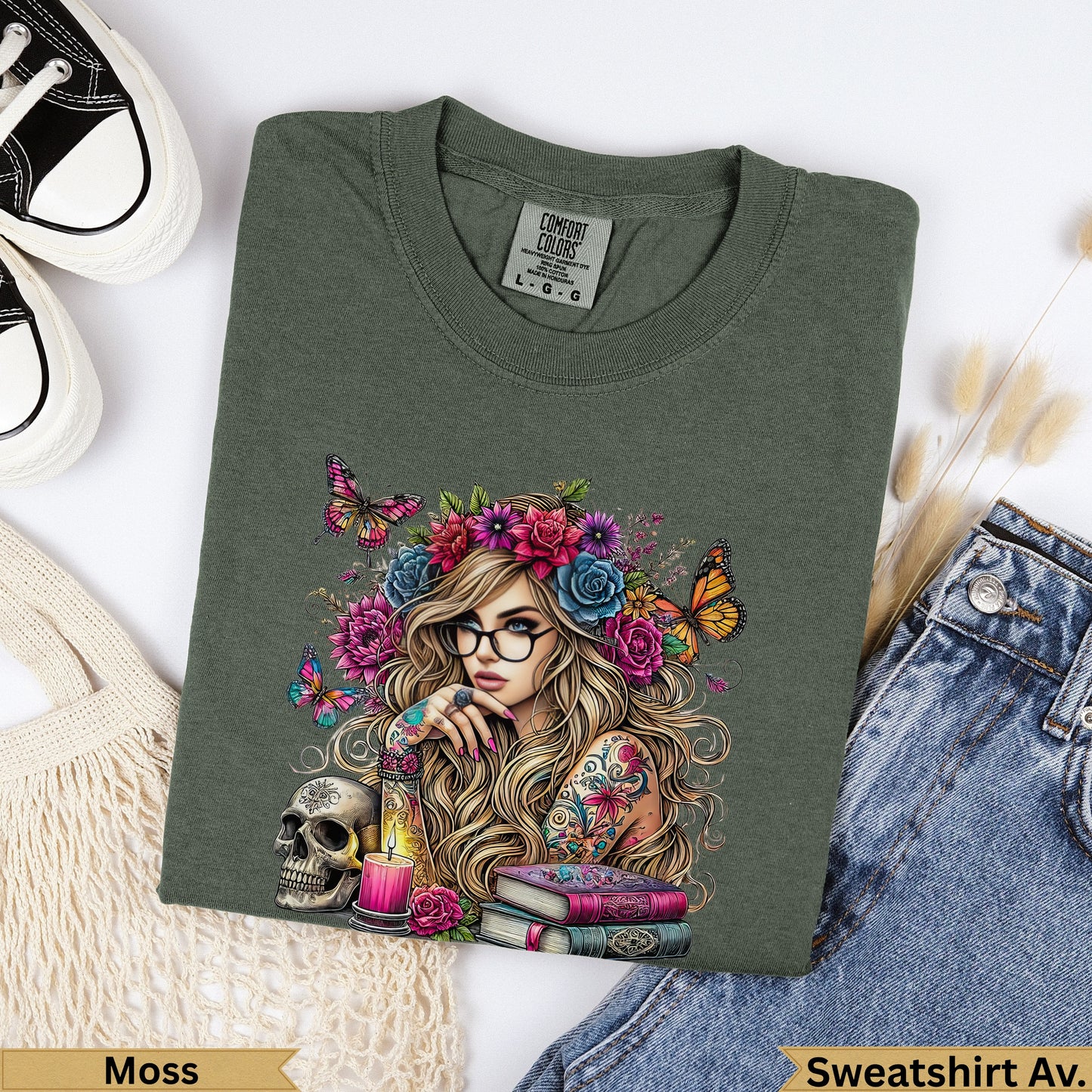 Olive green t-shirt with woman and floral crown artwork, skull, and books.
