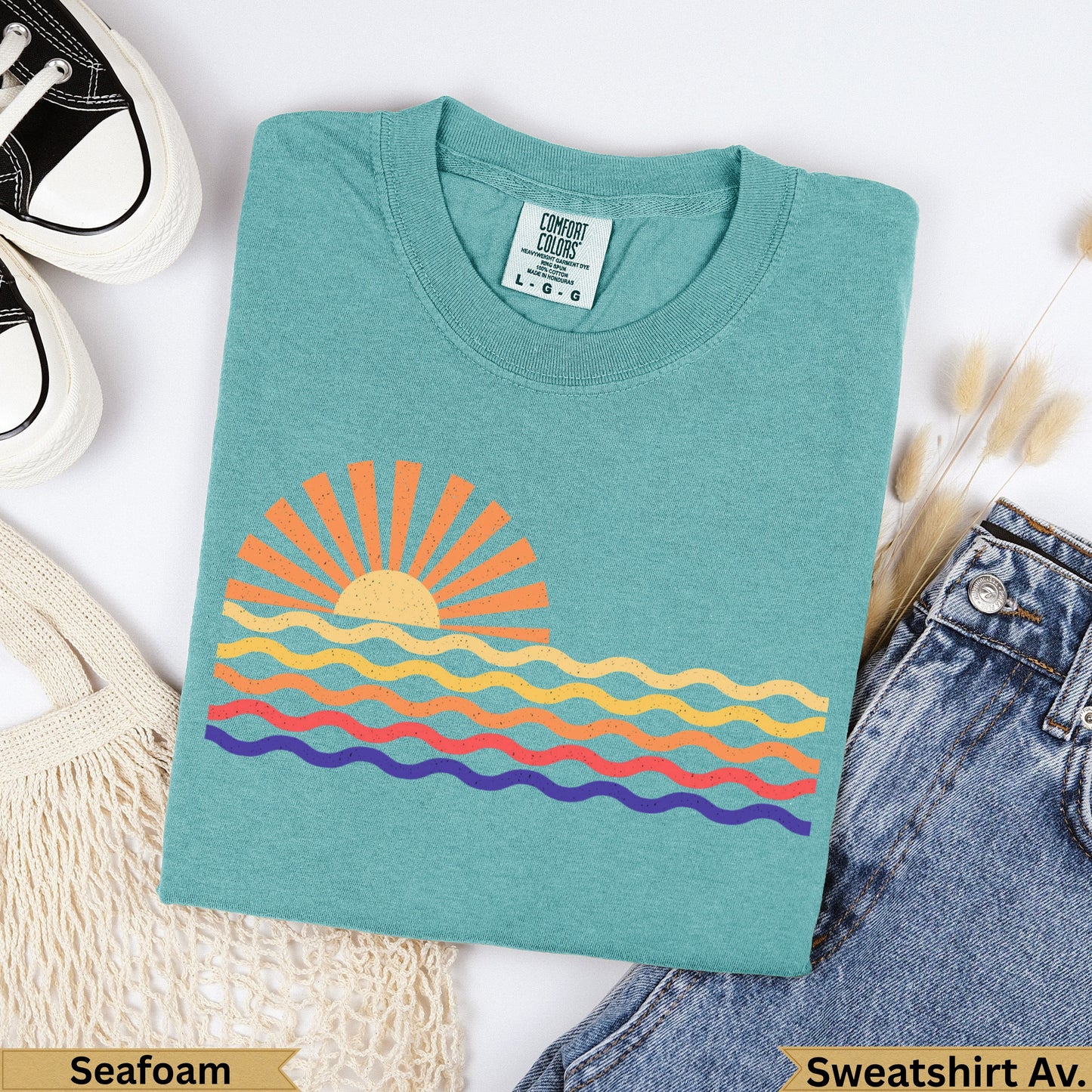 Teal Comfort Colors t-shirt with colorful wavy sun graphic, labeled "Seafoam" and "Sweatshirt Av.".
