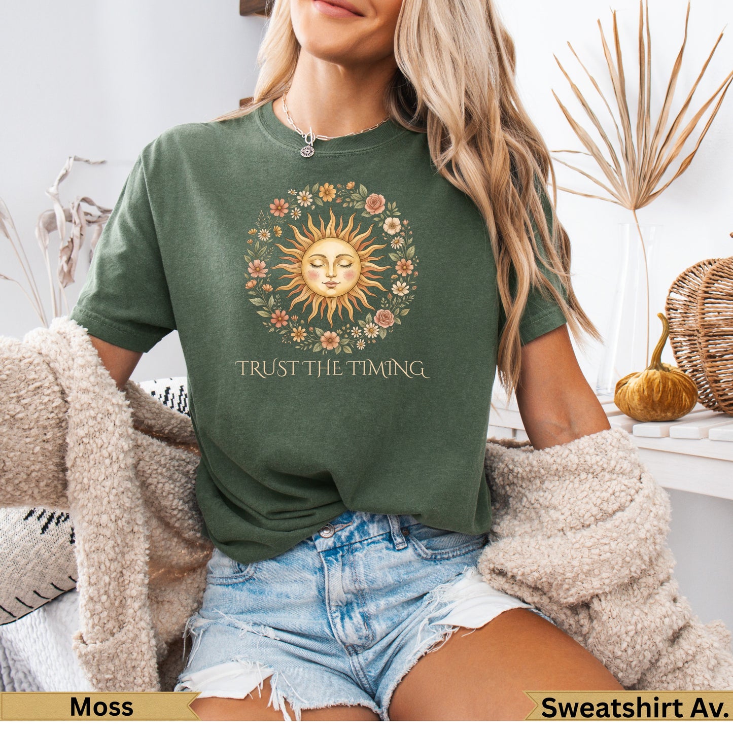 Moss green t-shirt with sun and floral graphic and "Trust The Timing" text.