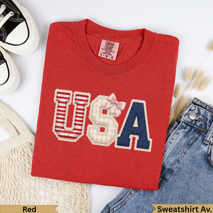 Red sweatshirt with "USA" in patriotic patchwork, bow.