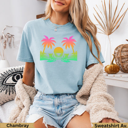 Light blue t-shirt with palm trees, beach chairs, and sunset graphic.