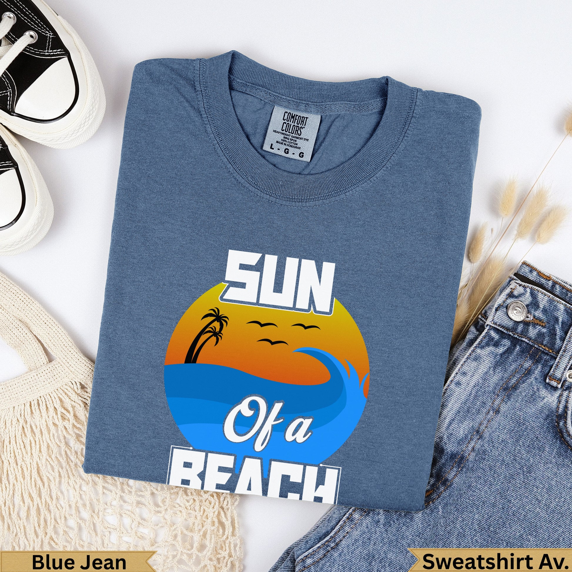 Blue t-shirt with "SUN Of a BEACH" graphic featuring a sunset over waves.