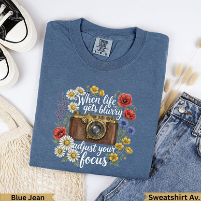 Blue t-shirt with vintage camera and floral graphic, "When life gets blurry adjust your focus".