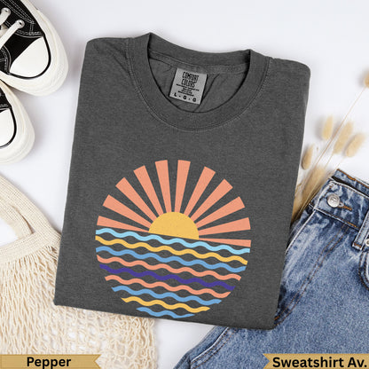 Dark grey Comfort Colors t-shirt with a sunset over wavy water graphic.