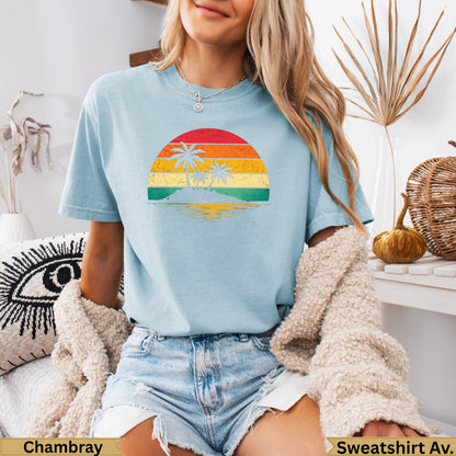 Light blue t-shirt with a retro sunset beach graphic and text.