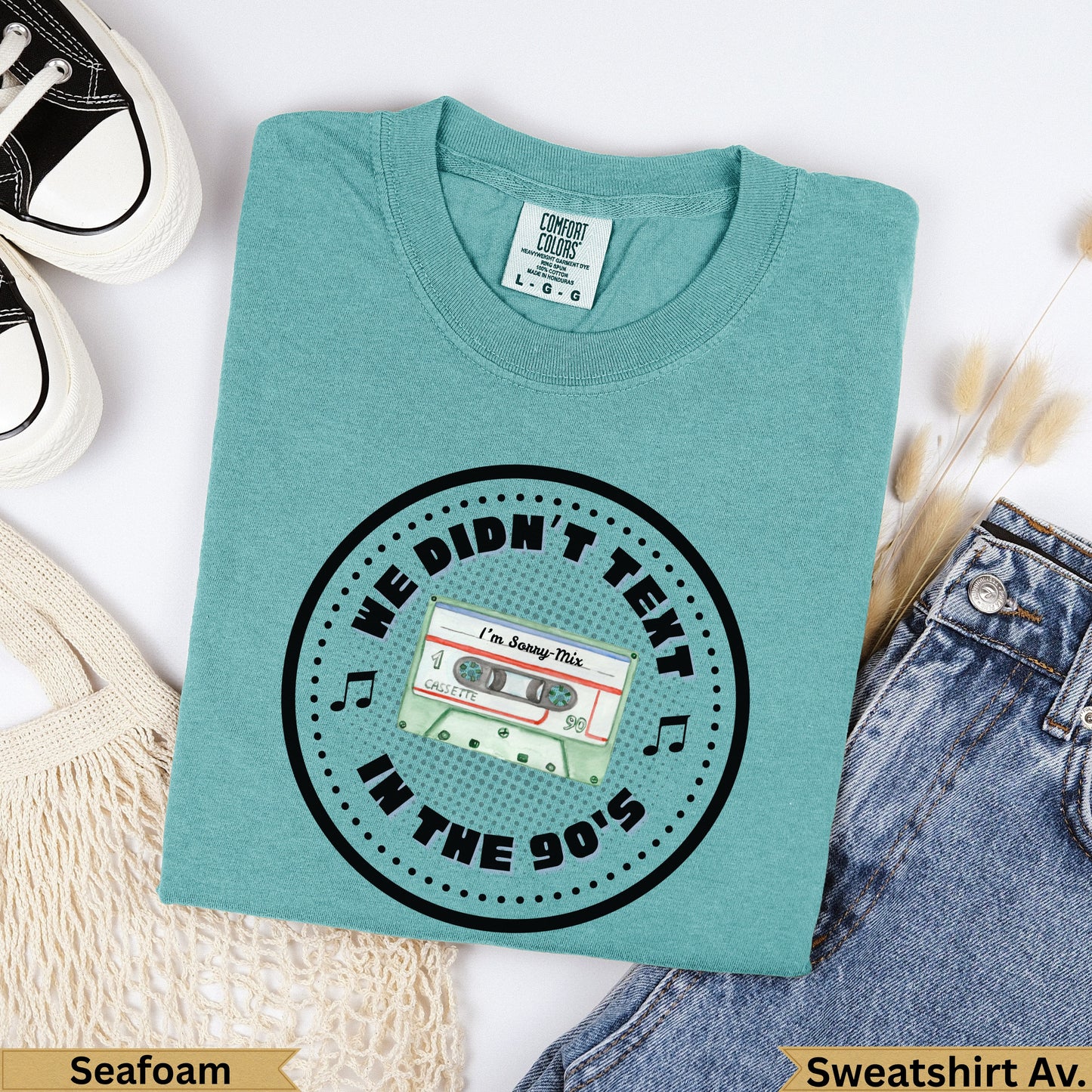 Teal crewneck sweatshirt with "We Didn't Text In The 90s" and cassette tape graphic.