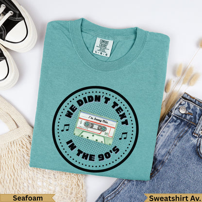 Teal crewneck sweatshirt with "We Didn't Text In The 90s" and cassette tape graphic.
