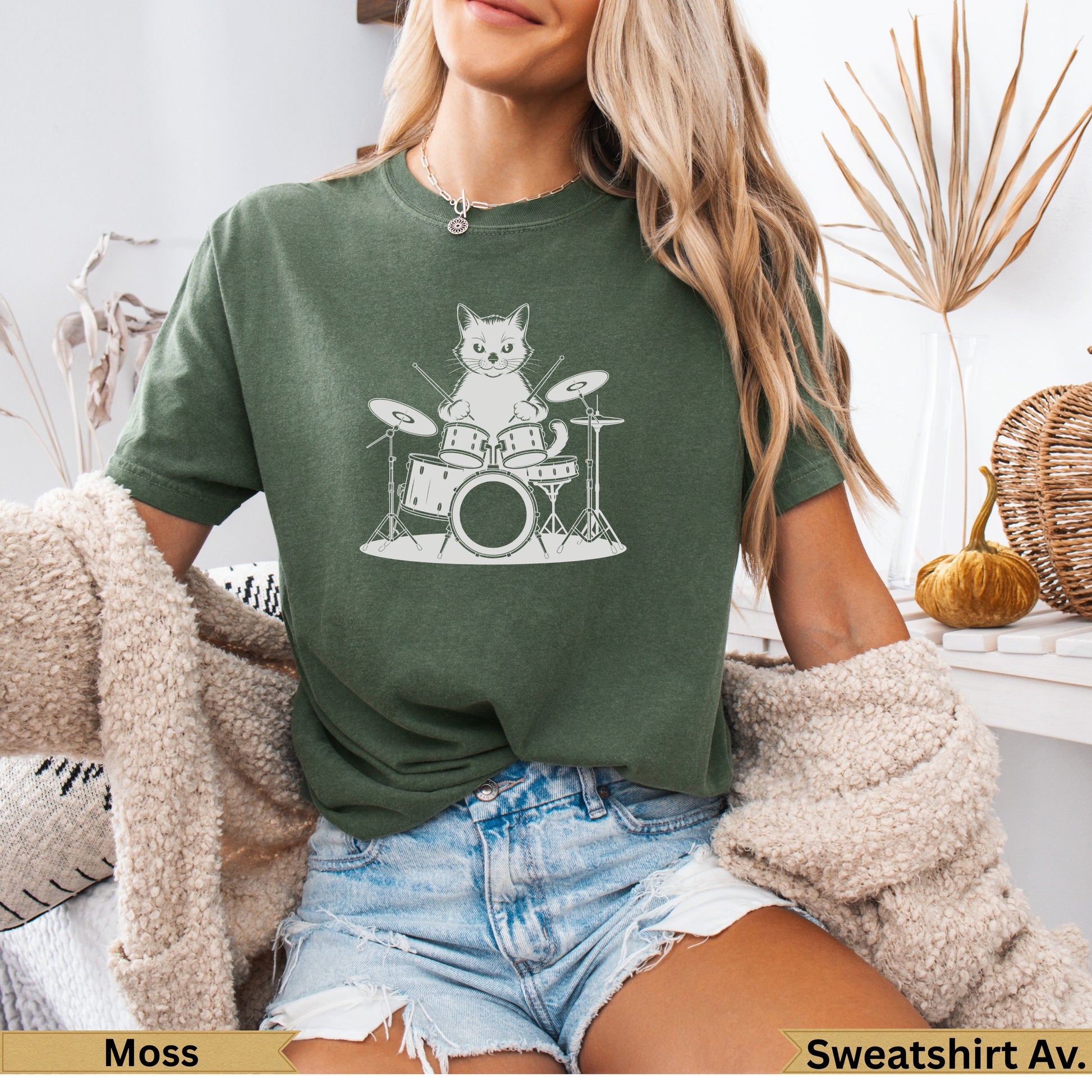 Cat drummer on drum set, dark green t-shirt.