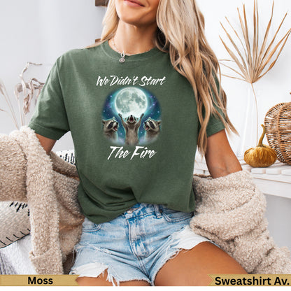 Green t-shirt with raccoons and moon graphic, "We Didn't Start The Fire" text.