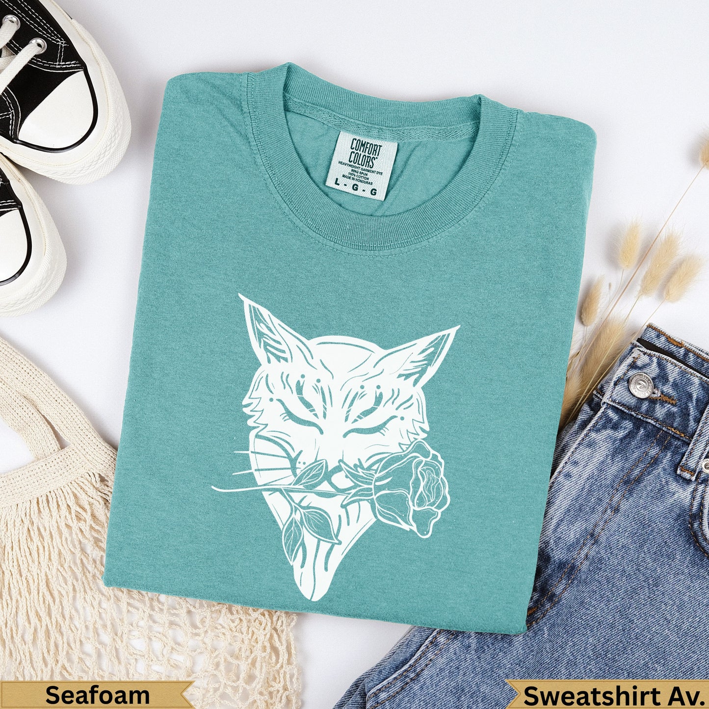 Teal sweatshirt with white bobcat and rose graphic, "Seafoam" and "Sweatshirt Av." text.