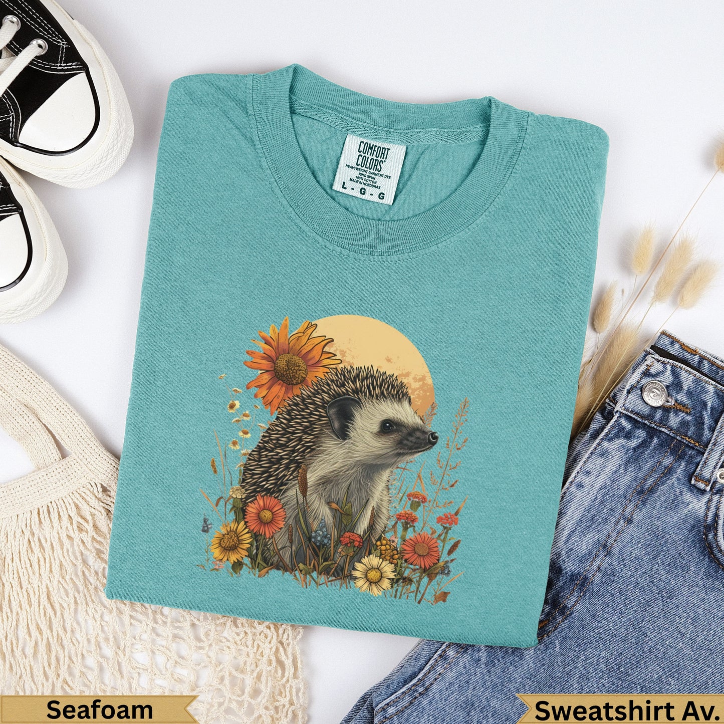Teal sweatshirt with hedgehog and floral graphic, "Seafoam" and "Sweatshirt Av." labels.