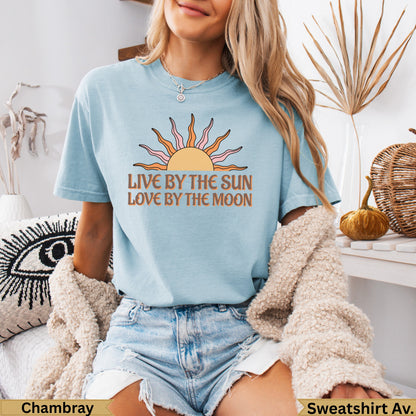 Light blue t-shirt with "Live by the sun, love by the moon" sun graphic.