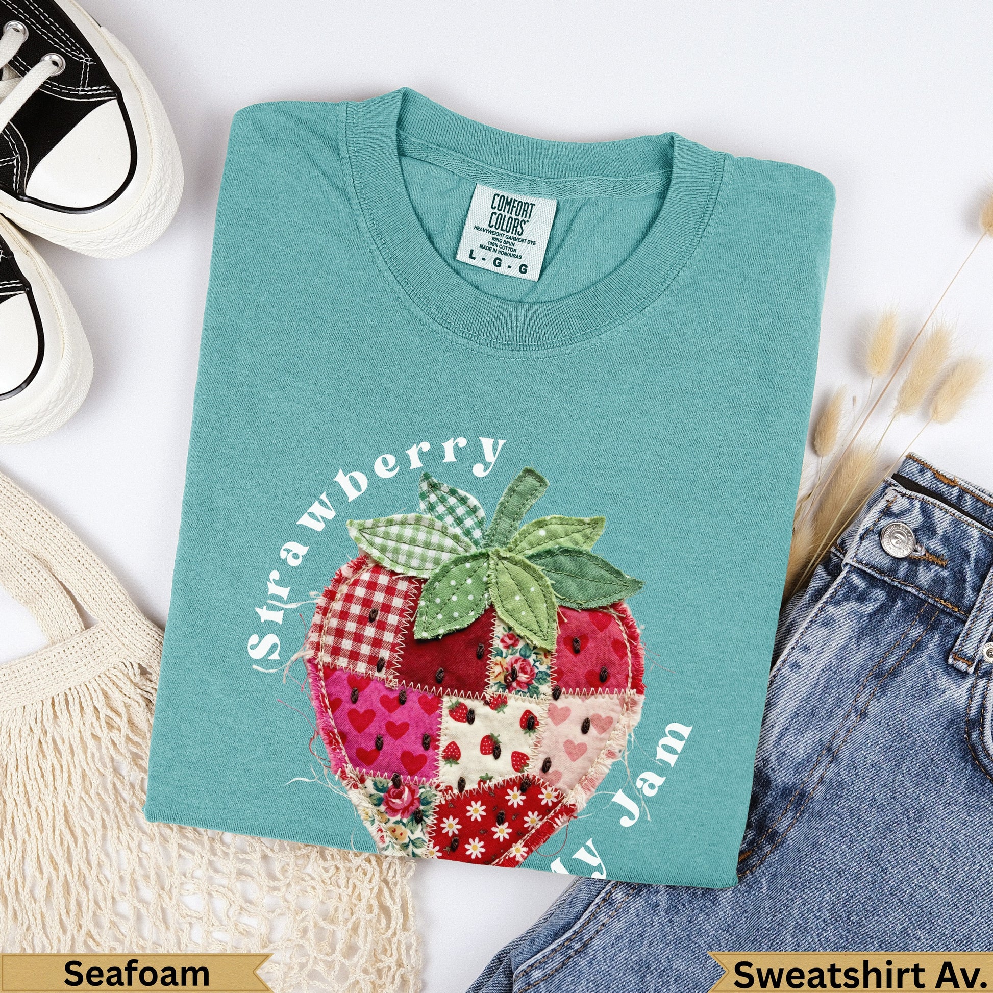Teal sweatshirt with a patchwork strawberry design and "Strawberry y Jam" text.