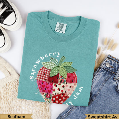 Teal sweatshirt with a patchwork strawberry design and "Strawberry y Jam" text.