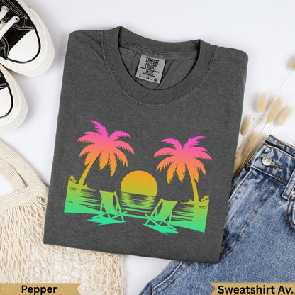 Dark gray t-shirt with sunset, palm trees, and beach chairs graphic.
