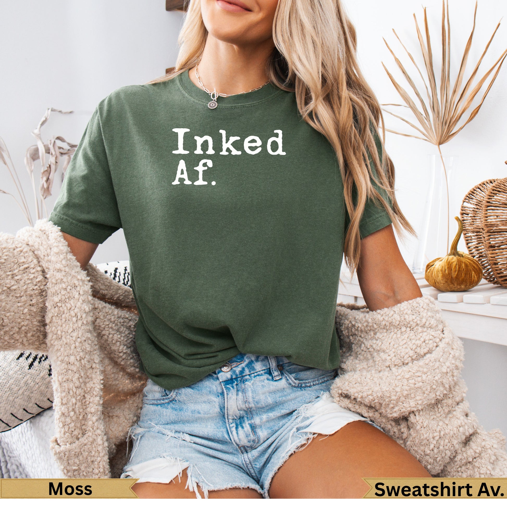 Woman wearing a dark green t-shirt with "Inked. Af." printed in white.