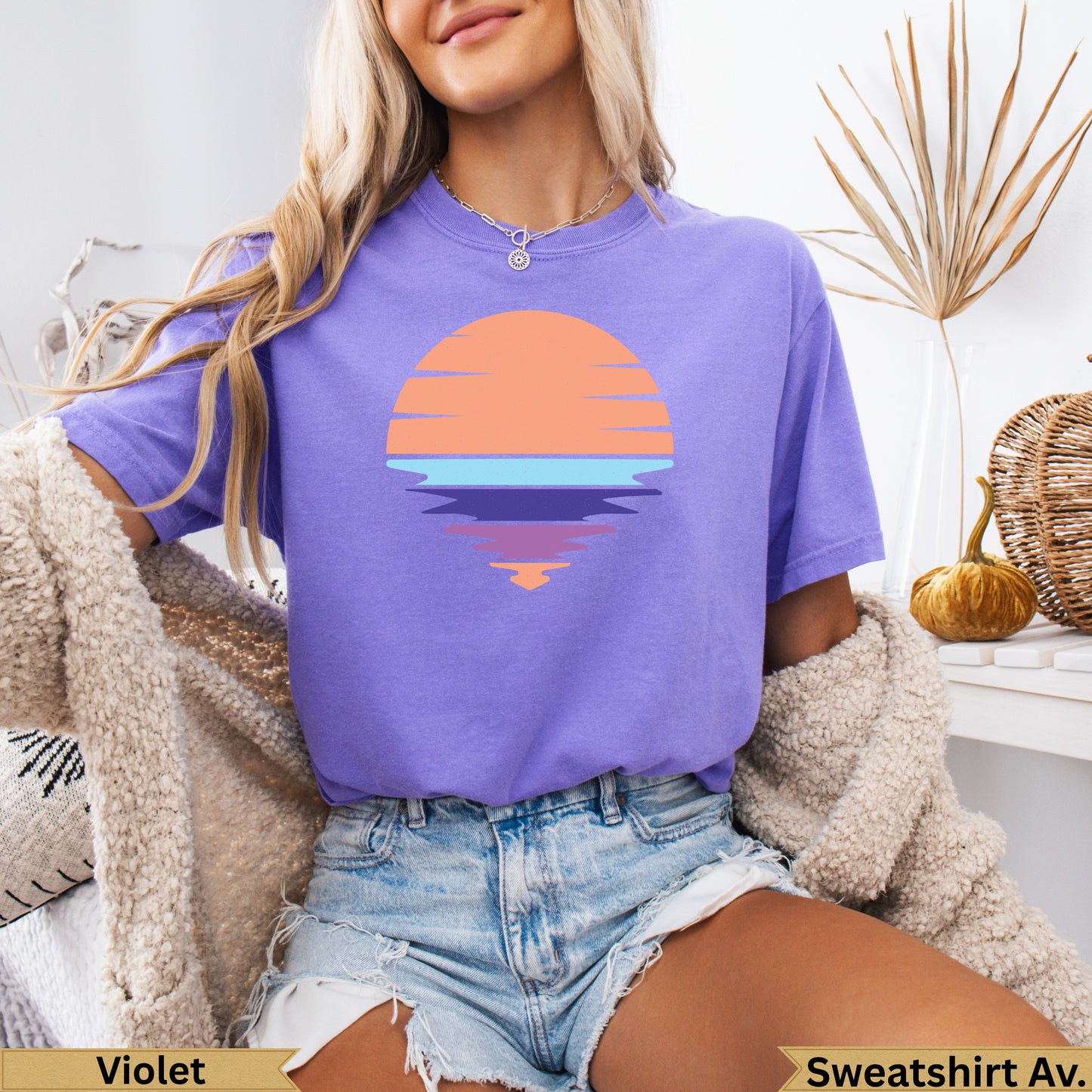Purple t-shirt with orange sunset graphic and reflection on water.