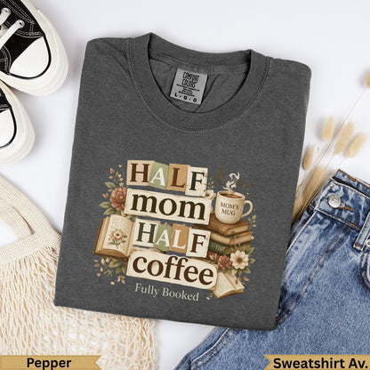 Dark gray sweatshirt with "Half mom, half coffee, fully booked" text and floral accents.