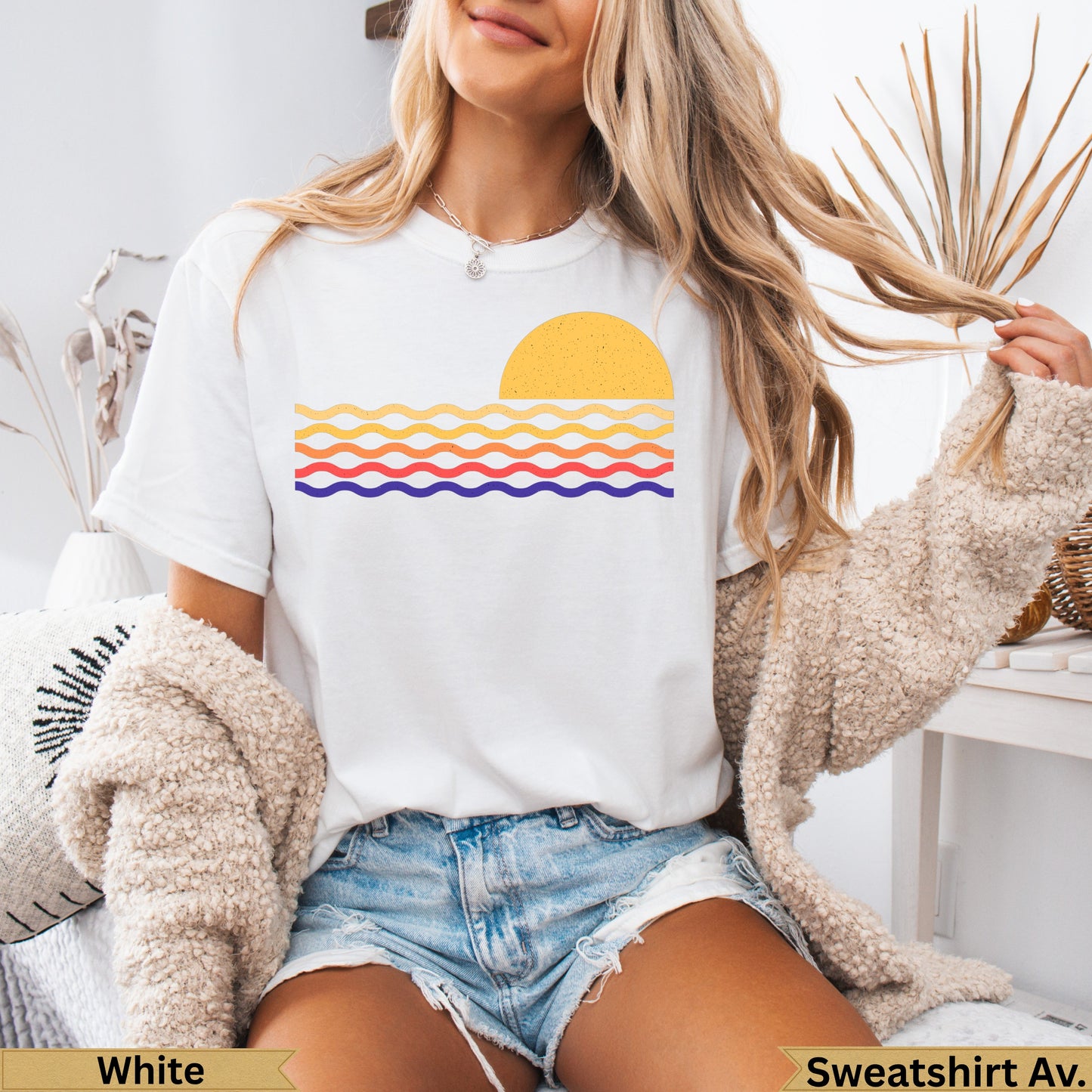 White t-shirt with a colorful sunset and wavy ocean graphic.