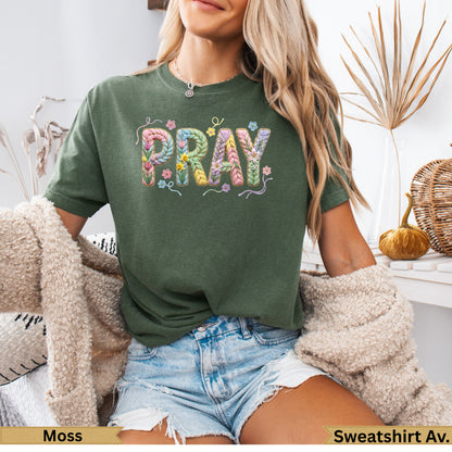 Moss green t-shirt with colorful, floral "PRAY" graphic.