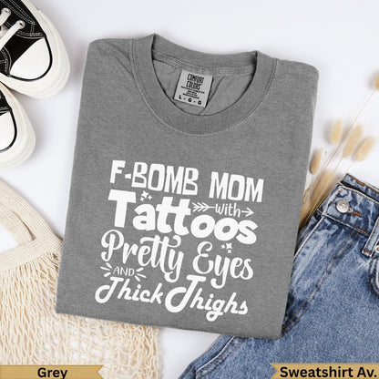 Grey t-shirt with "F-Bomb Mom" text, placed on jeans.