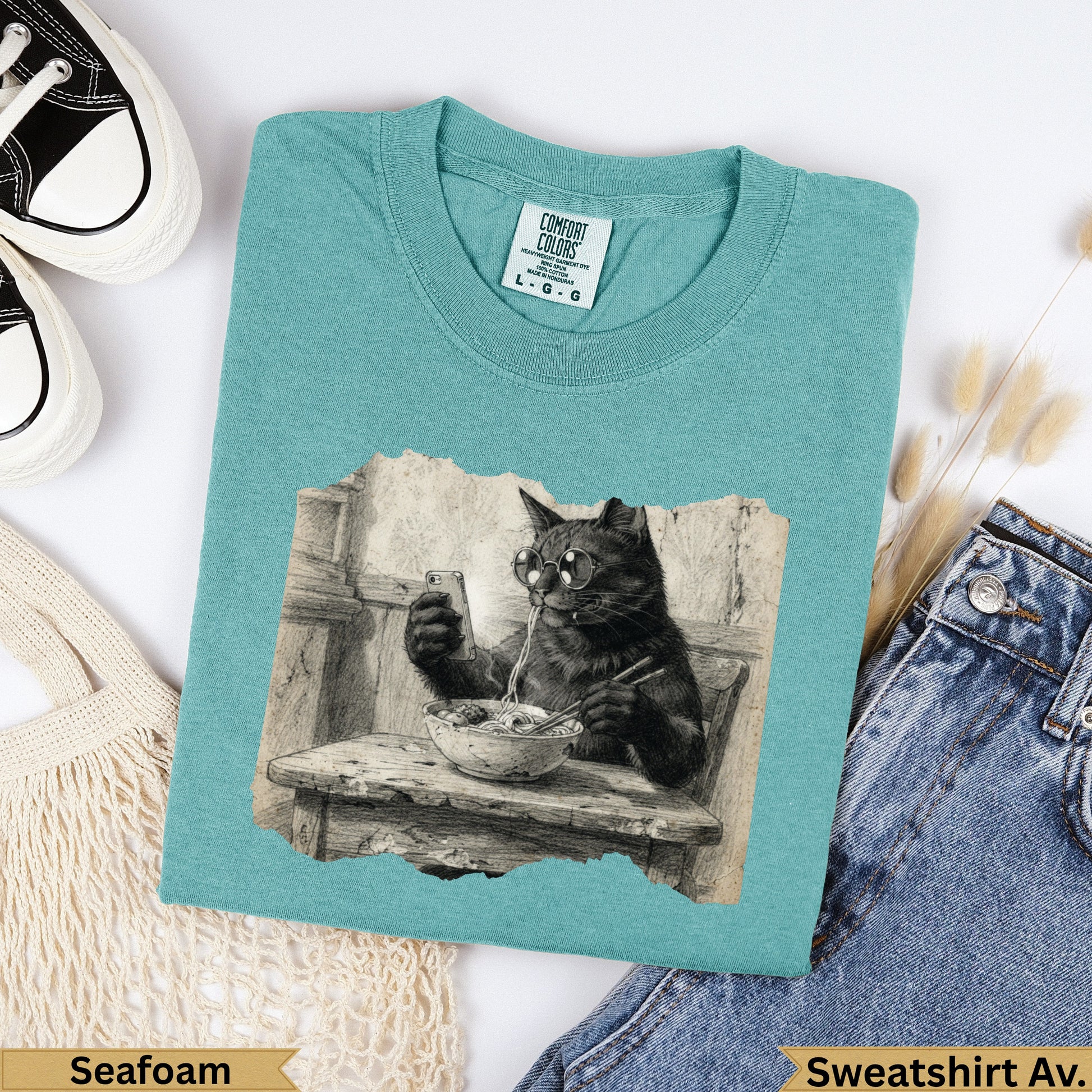 T-shirt with black cat wearing glasses eating noodles, "Seafoam Sweatshirt Av." text.