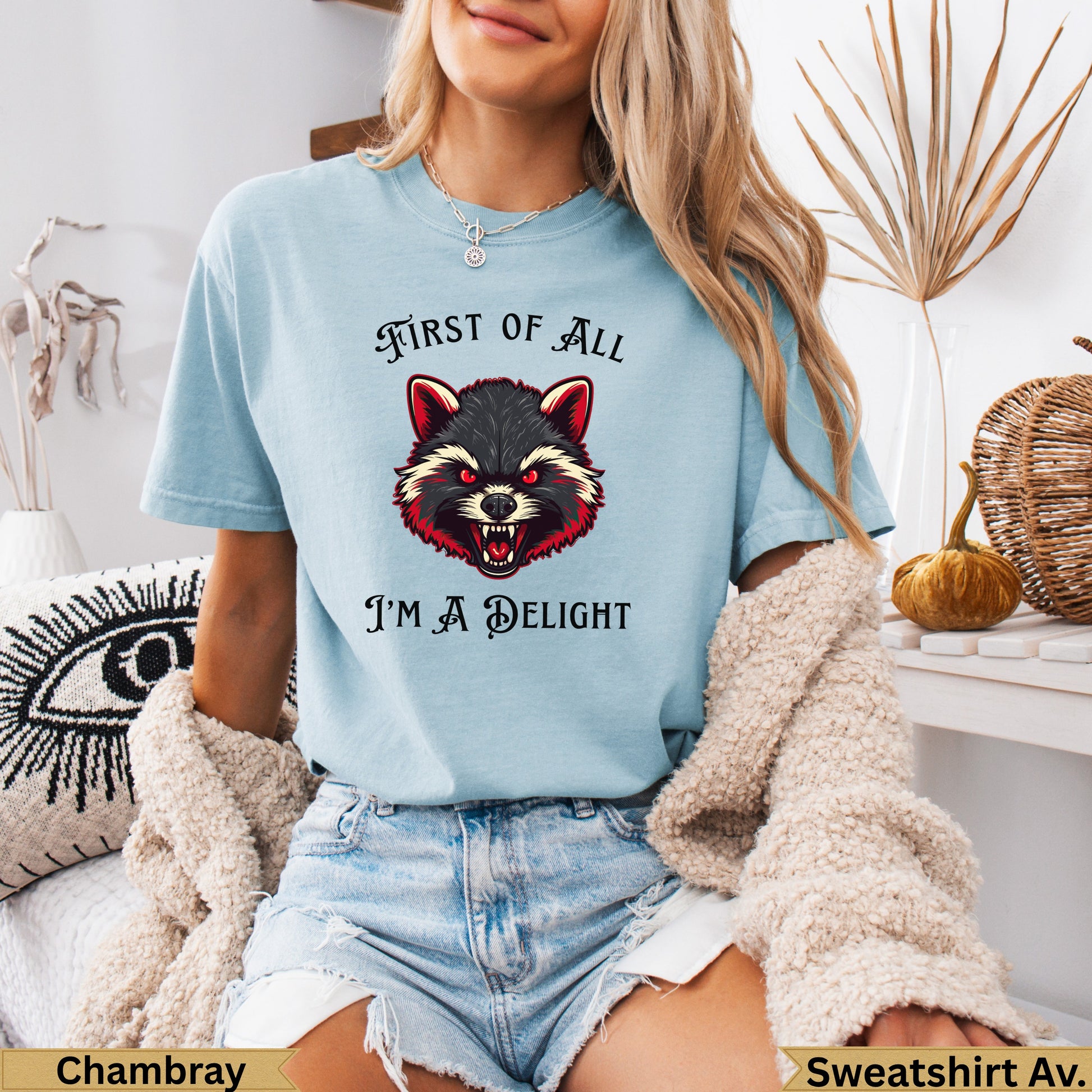 Light blue t-shirt with a fierce raccoon graphic and "FIRST OF ALL I'M A DELIGHT" text.