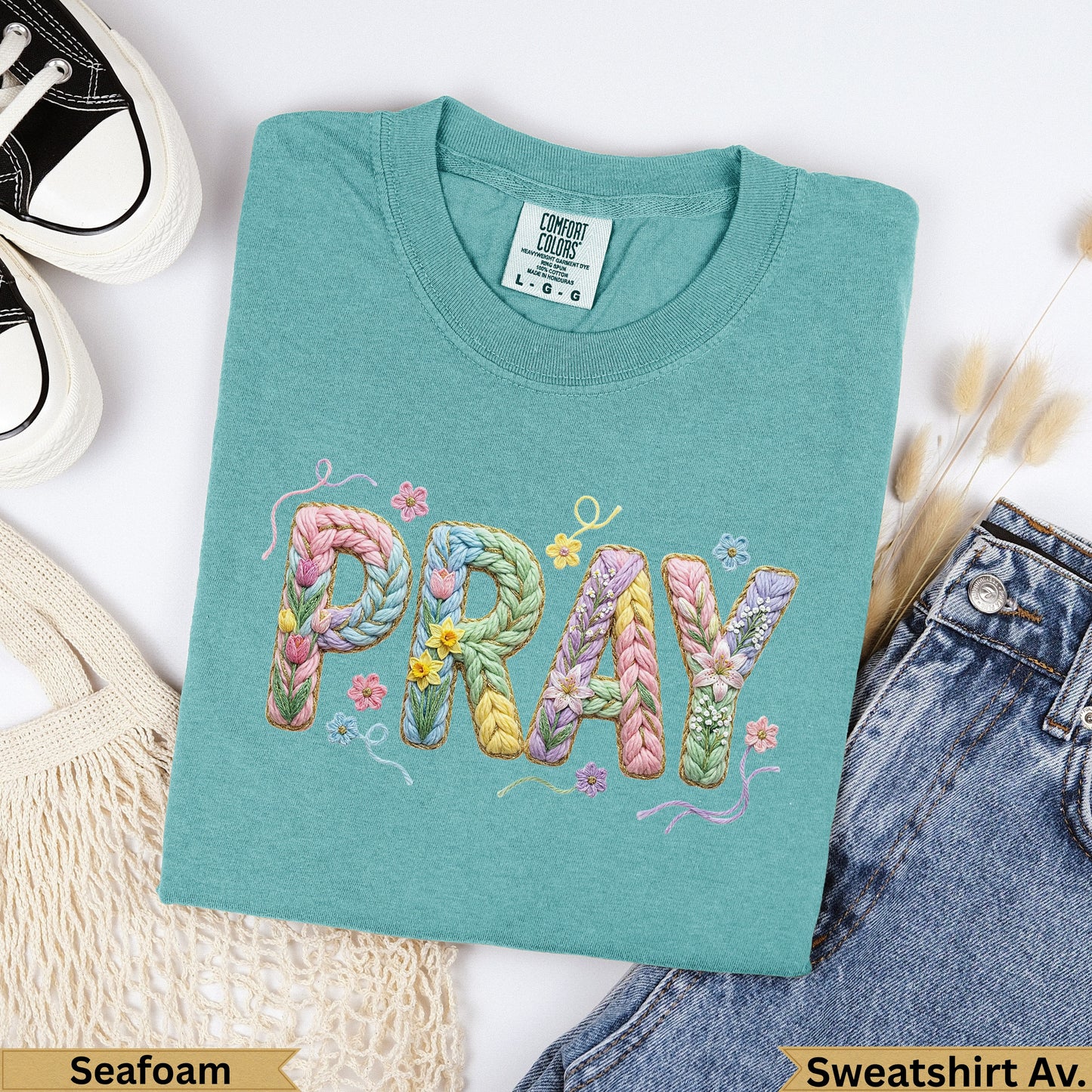 Teal sweatshirt with "PRAY" embroidered in colorful yarn letters.