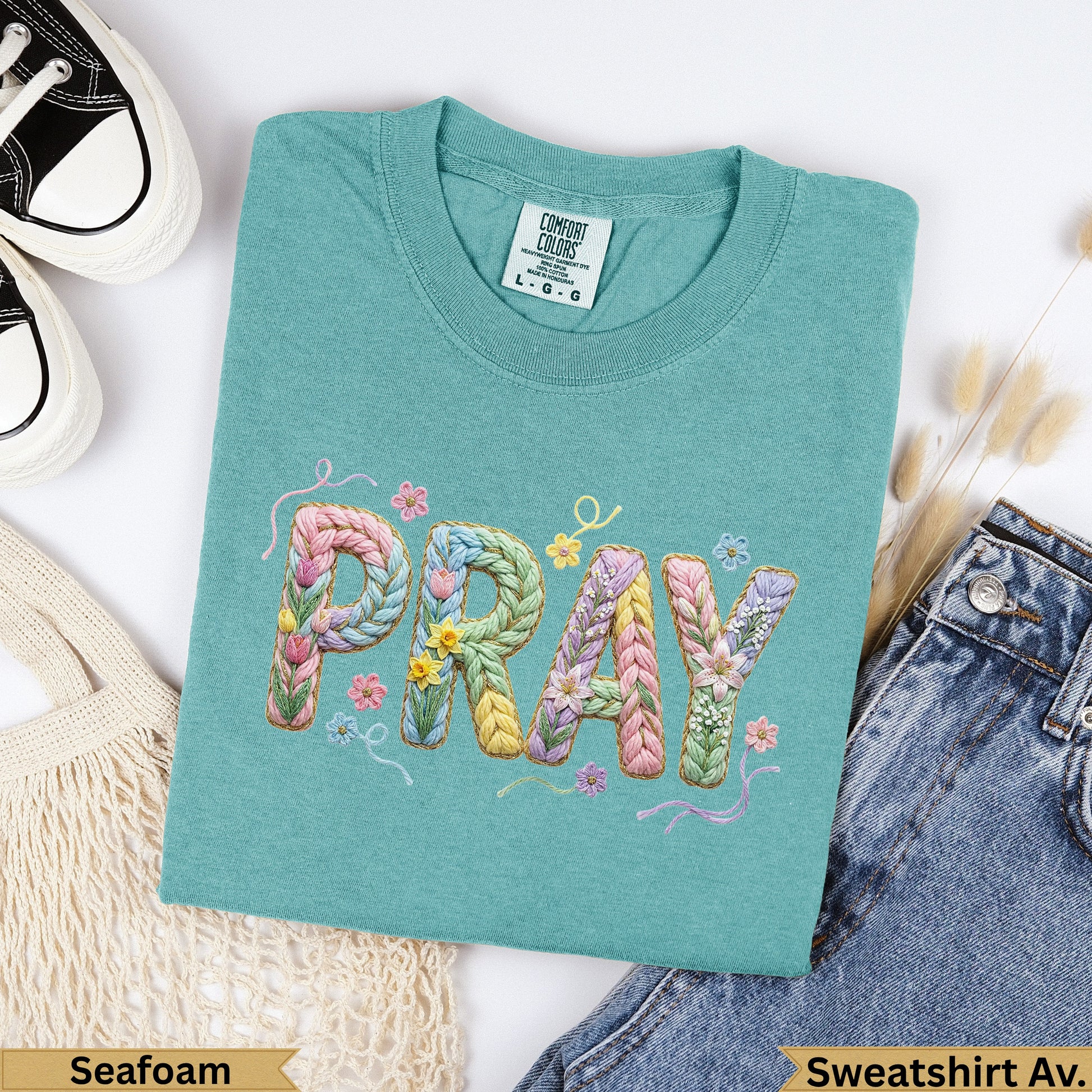 Teal sweatshirt with "PRAY" embroidered in colorful yarn letters.