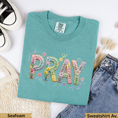 Teal sweatshirt with "PRAY" embroidered in colorful yarn letters.