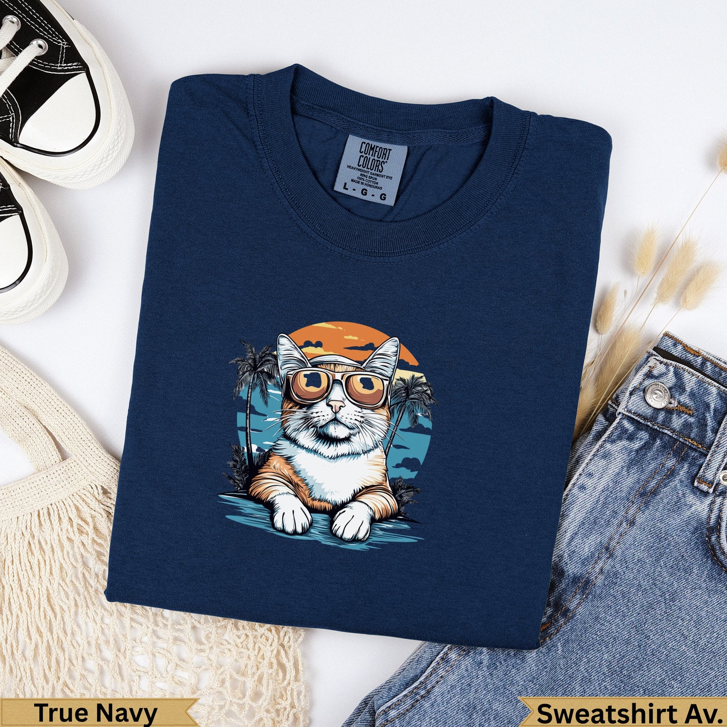 Navy t-shirt with a cartoon cat wearing sunglasses on a beach.