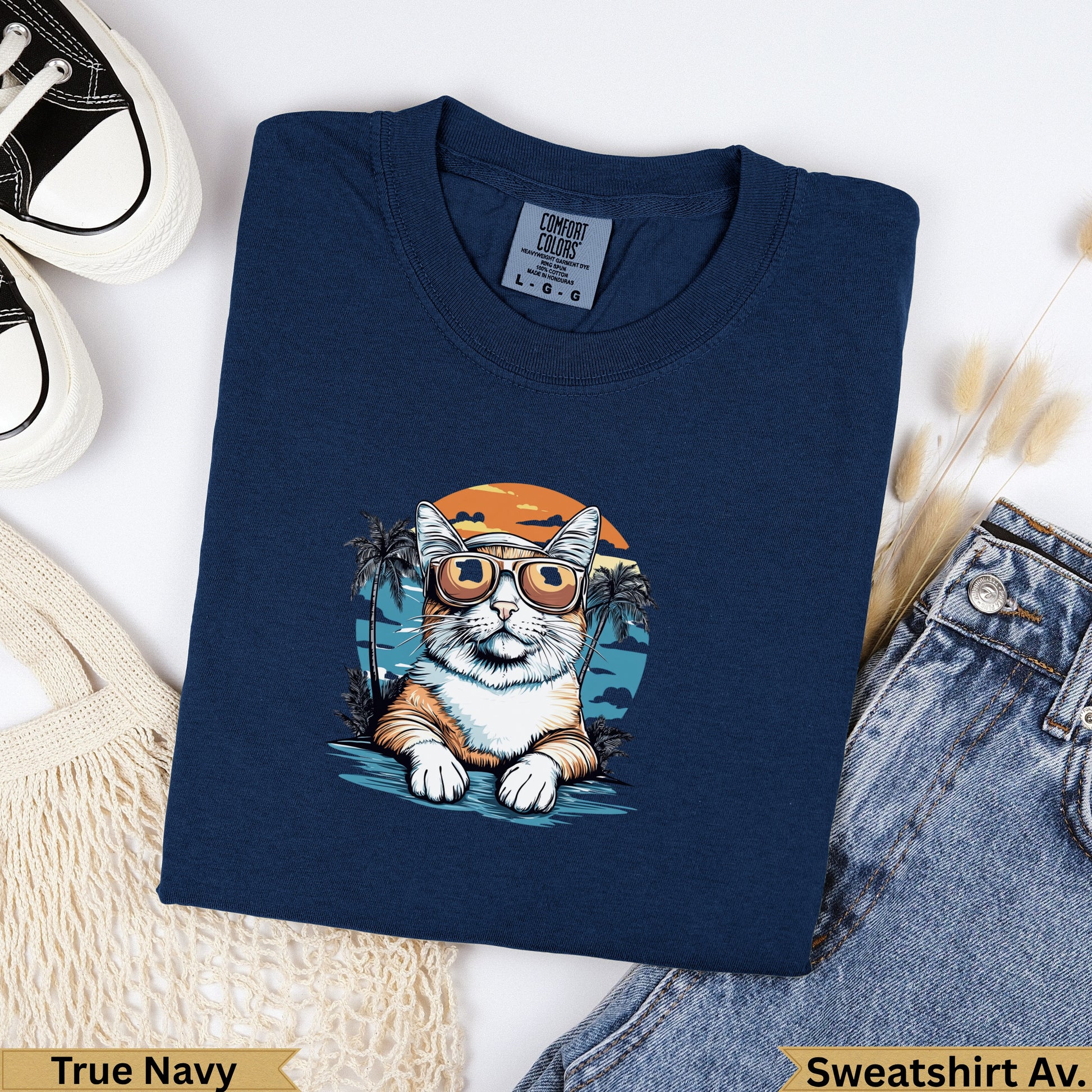 Navy t-shirt with a cartoon cat wearing sunglasses on a beach.