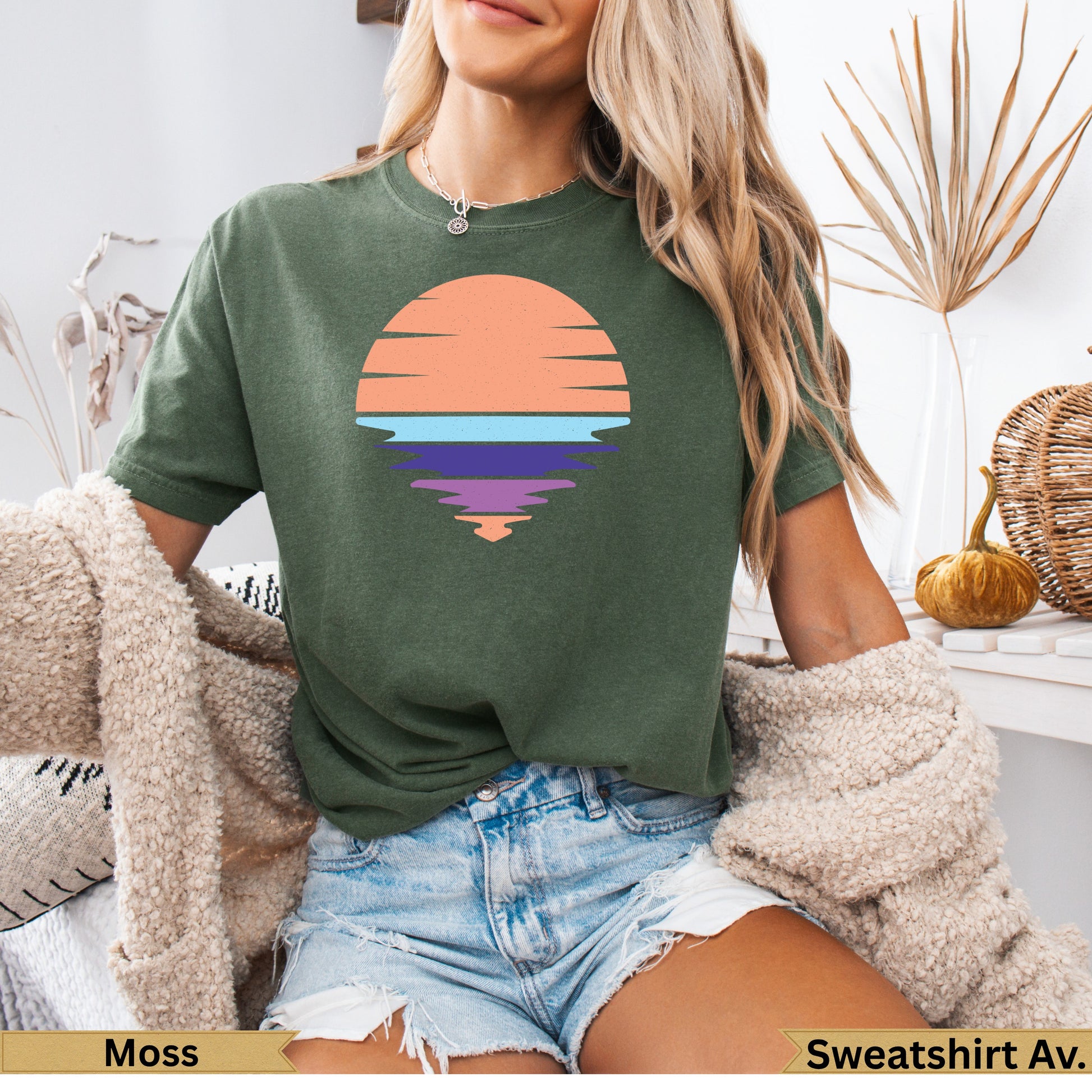 Green t-shirt with a sunset graphic and water reflection.