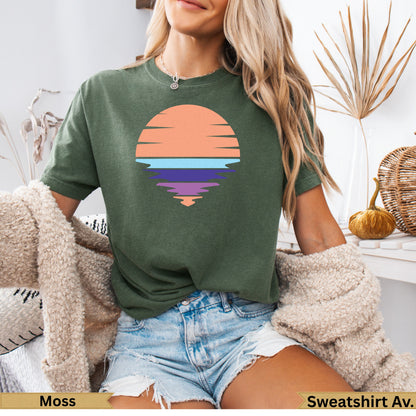 Green t-shirt with a sunset graphic and water reflection.