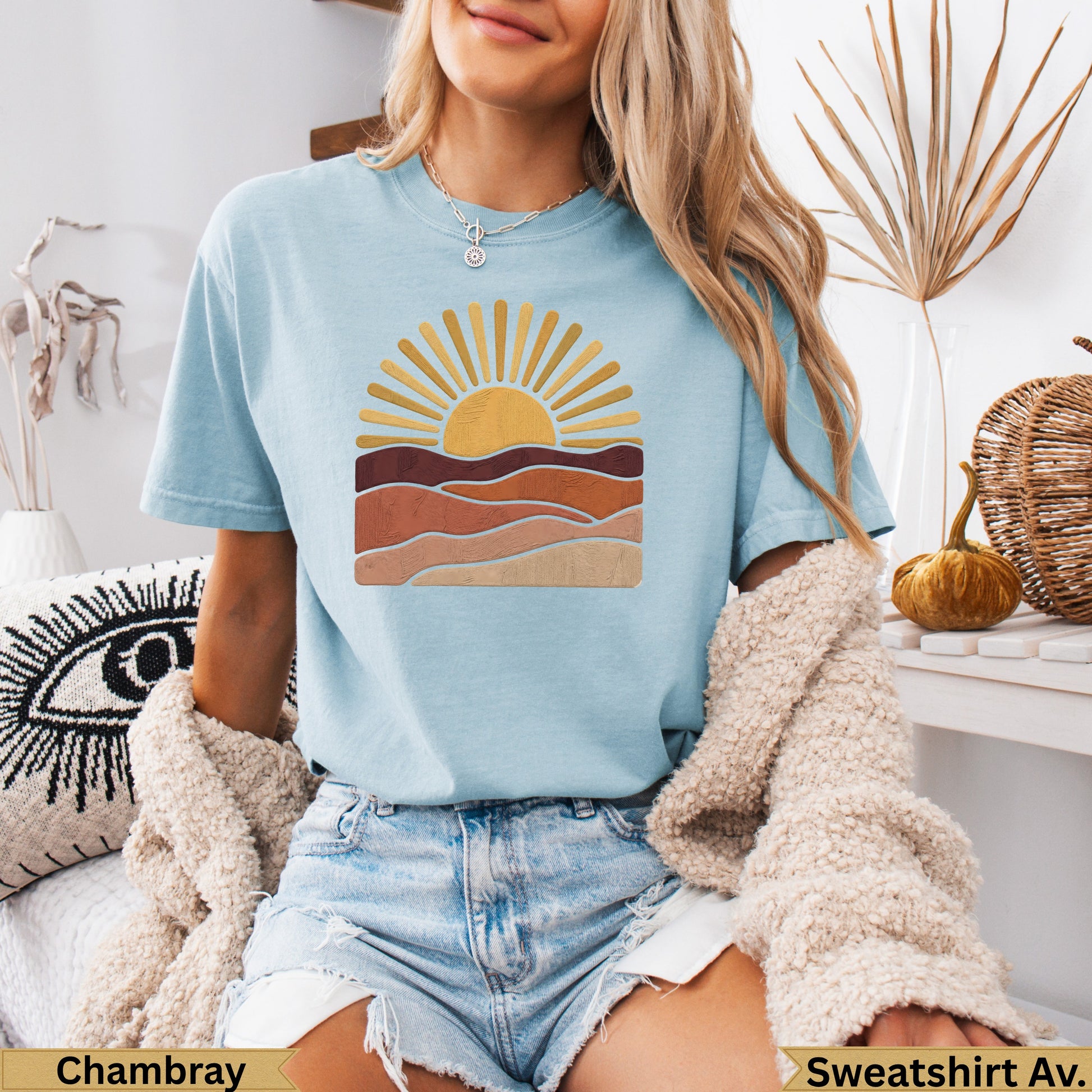 Light blue t-shirt with a stylized sunrise over desert landscape graphic.