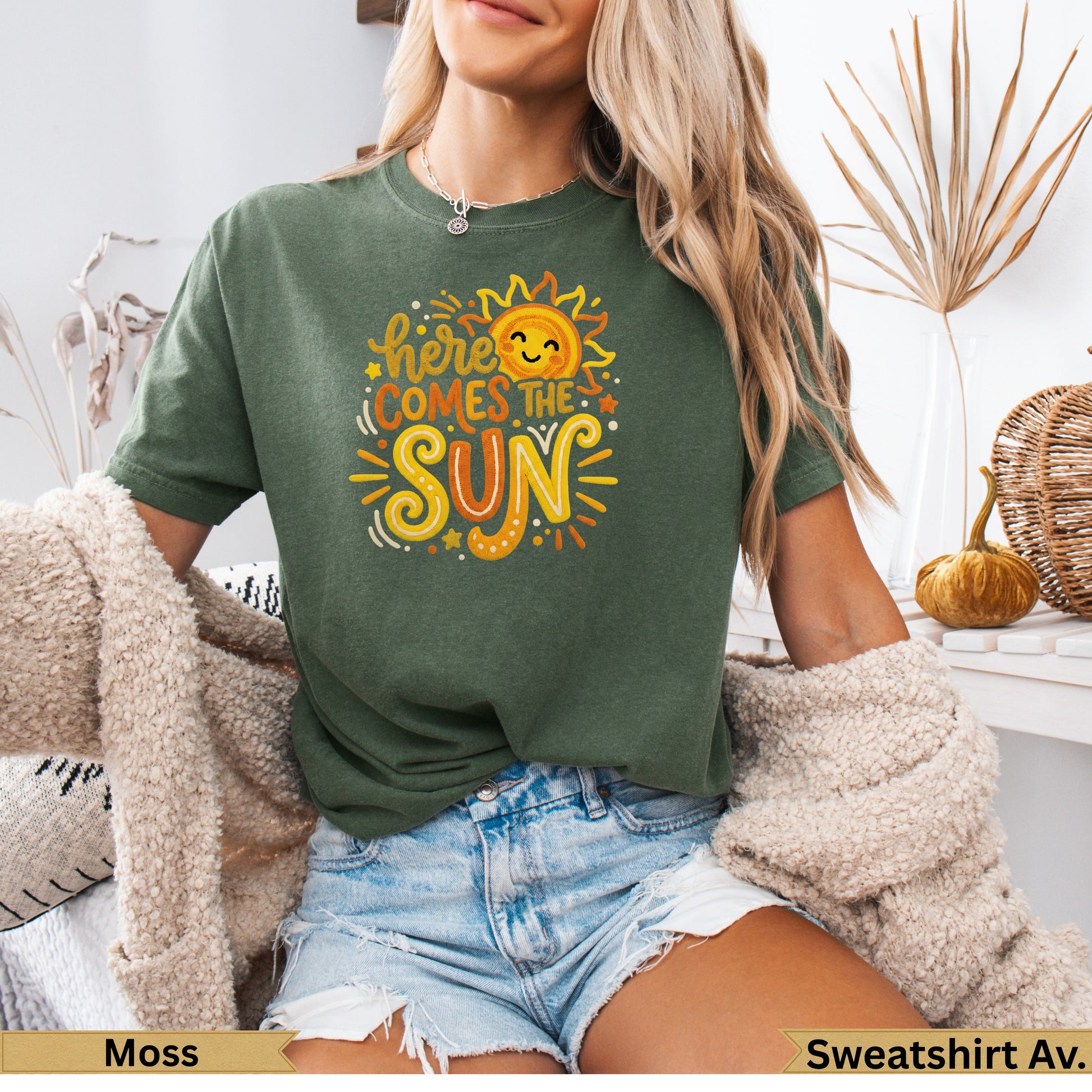 Green t-shirt with "Here comes the sun" graphic and a smiling sun illustration.