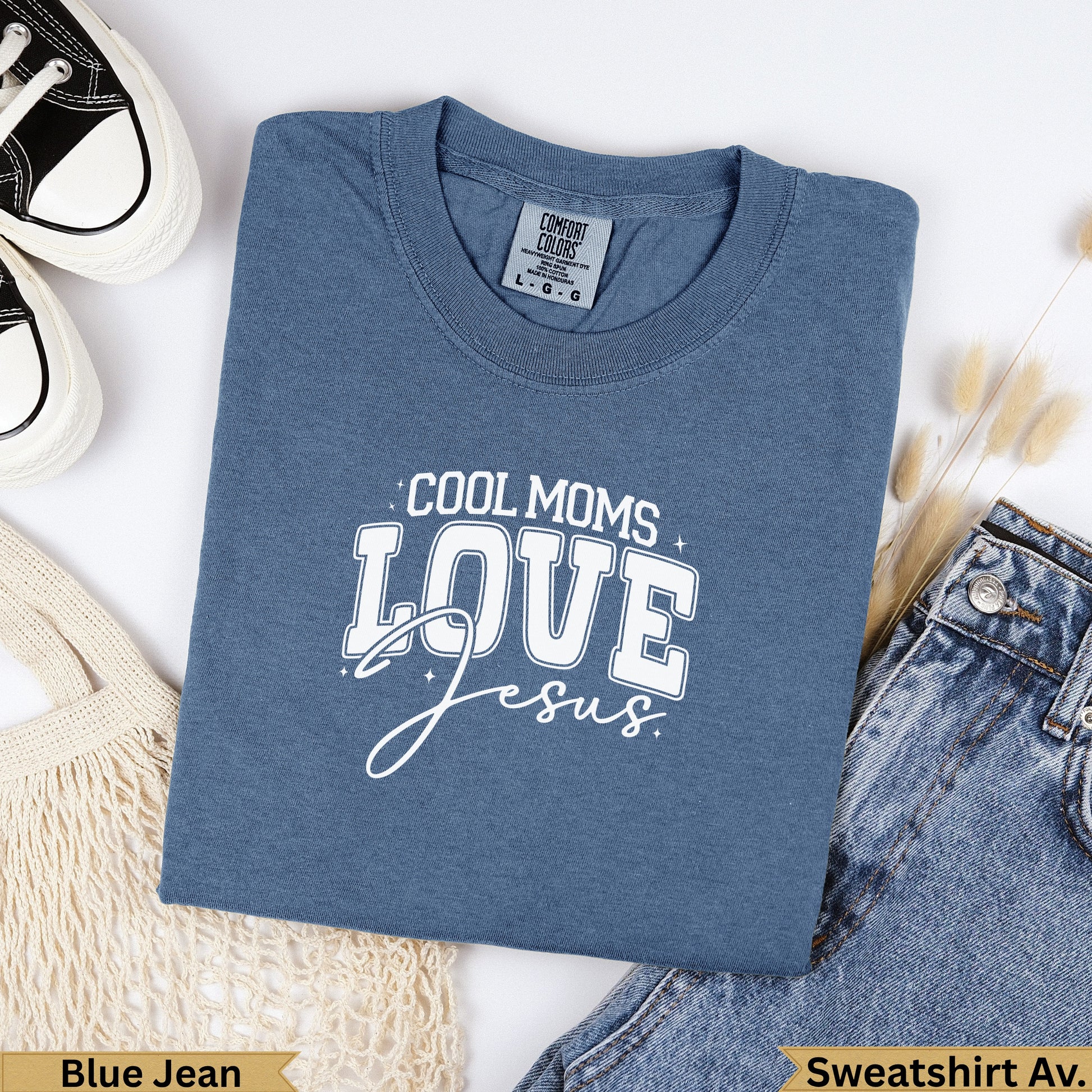 Blue t-shirt with "COOL MOMS LOVE Jesus" text, laid flat with jeans and shoes.