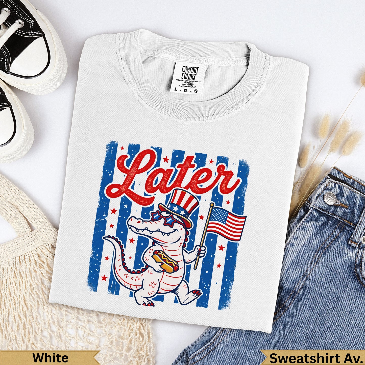White Comfort Colors t-shirt with cartoon alligator holding American flag and hot dog.
