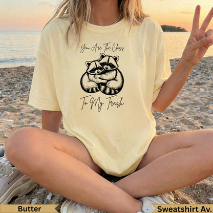 Butter yellow t-shirt with graphic of two raccoons and text "You Are The Class To My Trash".