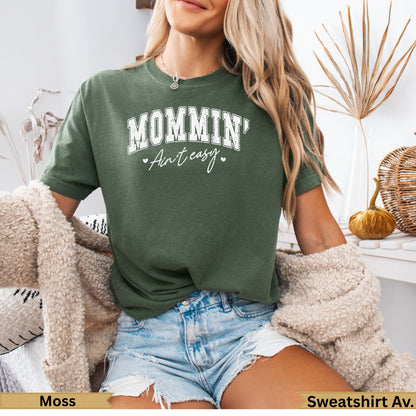 Green sweatshirt with "MOMMIN' Ain't Easy" text, worn by a woman.
